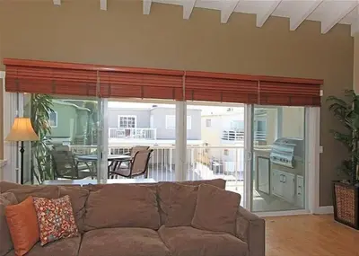 a living room with a brown couch and a balcony at 6BR Beach House w/ Bikes/Fire pit/BBQ/Easy Parking in Newport Beach