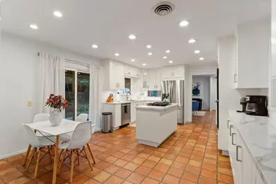 a kitchen with white cabinets and a table and chairs at Ocean View Retreat Firepit & Spacious Yard in San Diego