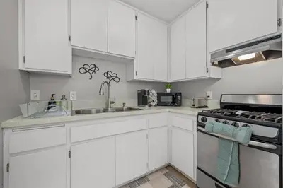 a kitchen with white cabinets and a sink and a stove at Prime North Park Stay, Walk to Restaurants, Bars, and Breweries with Free Parking in San Diego
