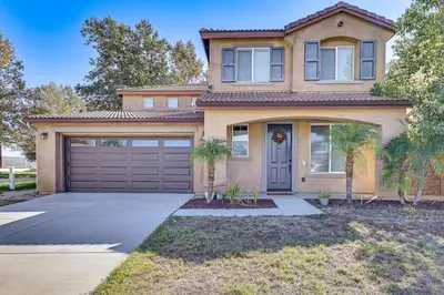 a house with a garage and palm trees in front of it at Spacious Menifee Home with Patio, 9 Mi to Lake! in Menifee