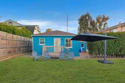 a blue house with a table and chairs and an umbrella at 10 Min to the Beach Colorful Home Huge Yard in San Diego