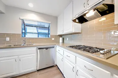 a kitchen with white cabinets and a stove top oven at Perfect Newport Beach Location With Balcony Spa II in Newport Beach
