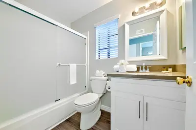 a white bathroom with a toilet and a sink at Perfect Newport Beach Location With Balcony Spa II in Newport Beach