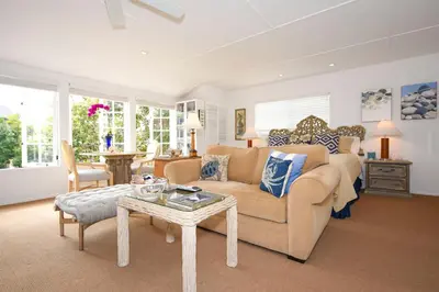 a living room with a couch and a table at Charming Garden Cottage with Full Kitchen Walk to La Jolla Village & Beaches in San Diego