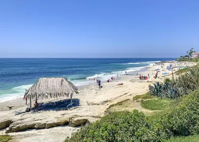 a beach with a straw umbrella and a crowd of people at Heart of La Jolla Village cottage in San Diego