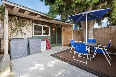 a patio with a table and chairs and an umbrella at Heart of La Jolla Village cottage in San Diego