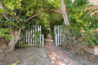 a white fence with a white gate and trees at Heart of La Jolla Village cottage in San Diego