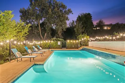 a swimming pool with chairs next to a fence with lights at Entire Private Home with 2 Bedrooms 1 Bathroom, Grand View, King Bed, Spacious, Parking, Available Now in El Cajon