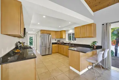 a kitchen with wooden cabinets and a stainless steel refrigerator at Oceanview Oasis with Roofdeck Hot Tub in Carlsbad