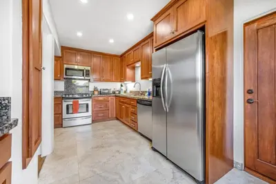 a kitchen with wooden cabinets and a stainless steel refrigerator at 2BR-2 mins to Ocean-Sleeps 8-Pets in San Diego