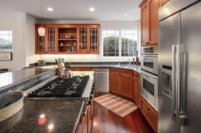 a kitchen with stainless steel appliances and wooden cabinets at Windansea Hideaway Rooftop Ocean Views in San Diego
