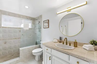 a bathroom with a toilet and a sink and a mirror at Sea Glass Beach Road Villa On the SAND Luxury and relaxation in Dana Point