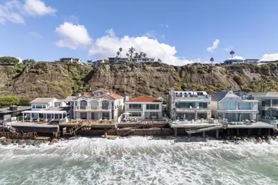 a group of houses on the beach next to the water at Sea Glass Beach Road Villa On the SAND Luxury and relaxation in Dana Point