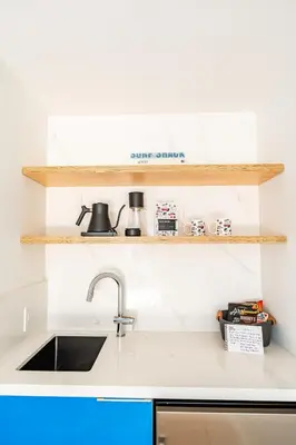 a kitchen counter with a sink and wooden shelves at Simple La Jolla Epic bungalow #7 in San Diego