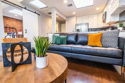 a black leather couch in a living room with a table at Gaslamp 2BR Upscale Queen Beds with Smart TV in San Diego