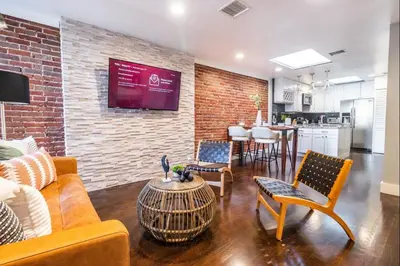 a living room with a couch and chairs and a brick wall at Family-Friendly Apartment with Kitchen in San Diego