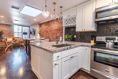 a kitchen with white cabinets and a brick wall at Family-Friendly Apartment with Kitchen in San Diego