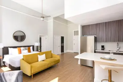 a bedroom with a bed and a yellow chair and a kitchen at Gaslamp Loft Escape Sleeps 7 in Style in San Diego