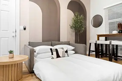 a bedroom with a bed with white sheets and a table at Relax in Stylish 1BR Near Gaslamp and Little Italy in San Diego