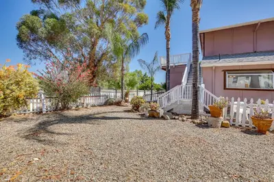 a house with a white fence and palm trees at 4 Mi to Lake Elsinore Pet-Friendly Adventure Base in Lake Elsinore