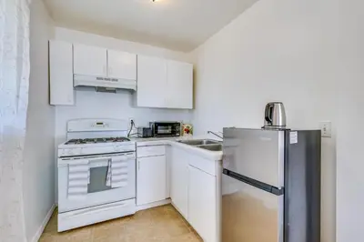 a kitchen with white cabinets and a refrigerator at 4 Mi to Shore Lake Elsinore Studio with Mtn Views in Lake Elsinore