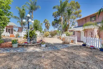 a house with a white fence and palm trees at Lake Elsinore Apt 4 Mi to Water Pets Welcome! in Lake Elsinore