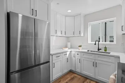 a kitchen with white cabinets and a stainless steel refrigerator at Modern Organic Getaway - New 2 Bed 2 Bath - Close to Beaches & Downtown in San Diego