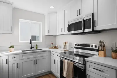 a white kitchen with white cabinets and a stove top oven at Modern Organic Getaway - New 2 Bed 2 Bath - Close to Beaches & Downtown in San Diego