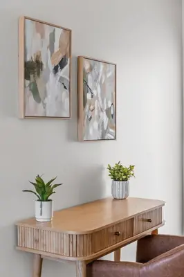a wooden table with two plants on a wall with two pictures at Modern Organic Getaway - New 2 Bed 2 Bath - Close to Beaches & Downtown in San Diego