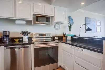 a kitchen with white cabinets and stainless steel appliances at Ocean 11 condo in Solana Beach