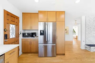 a kitchen with a stainless steel refrigerator and wooden cabinets at PB Ocean Views - Garage, Parking, King Bed in San Diego
