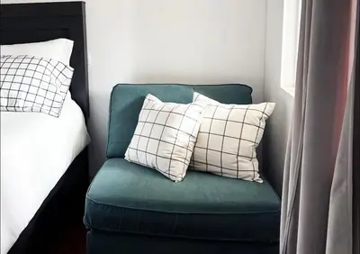 a green chair with two pillows next to a bed at Mira Mesa Private Suite with Private Bath & Entry #2 in San Diego