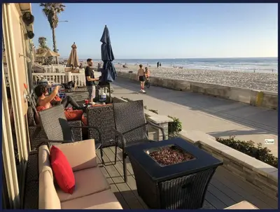 a person sitting on a patio near the beach at Ocean Front Beauty right on Best Beach in Mission Beach, San Diego! in San Diego