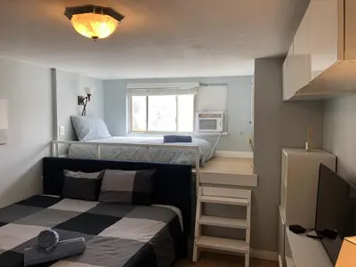 a small room with two beds and a television at Ocean Front Beauty right on Best Beach in Mission Beach, San Diego! in San Diego