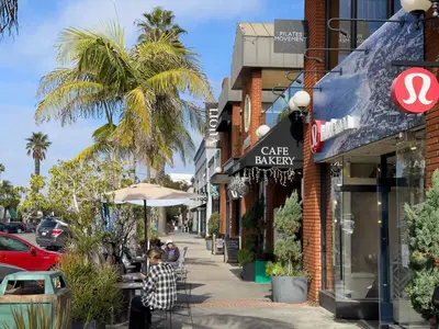 a city street with a cafe bakery and palm trees at La Jolla Village Escape - Walk to Everything in San Diego