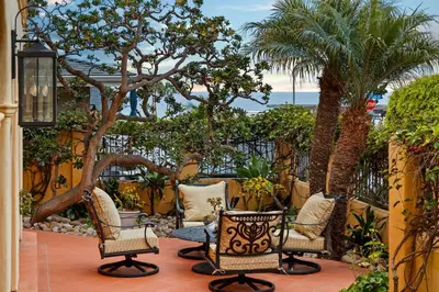 a patio with chairs and palm trees and the ocean at Lush by the Sea in San Diego