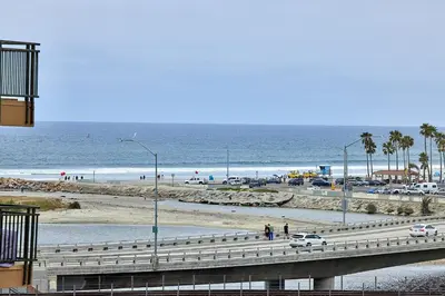 a beach with cars parked on a bridge and the ocean at SeaCliff Costa Pacifica -1310 in Oceanside