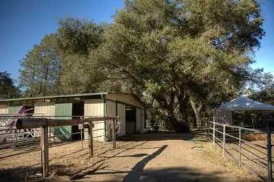 a building with a tree and a fence at Peaceful Mountain Tent Escape at Harrison Ranch in Pauma Valley