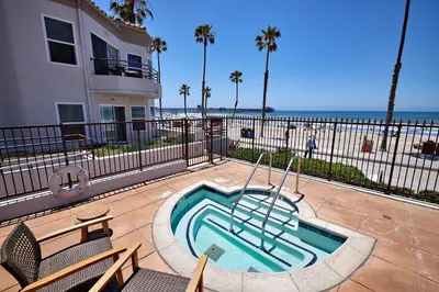 a swimming pool next to a building and the beach at 501P-5 Panoramic Ocean & Pier Views in Oceanside