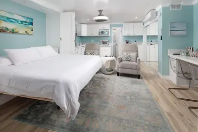 a bedroom with a white bed and a kitchen at Suite with Rooftop Deck and Ocean Views in Mission Bay in San Diego