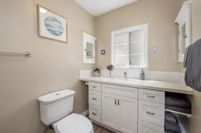 a white bathroom with a toilet and a sink at Ben's Beach Bungalow 1 150 Steps to Sand in San Diego