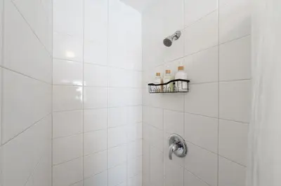 a bathroom with a shower with white tiles at Ben's Beach Bungalow 1 150 Steps to Sand in San Diego