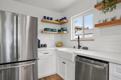 a kitchen with white cabinets and a stainless steel refrigerator at Spectacular Coastal Farmhouse 4BR in Ocean Beach in San Diego