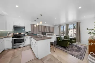 a kitchen with white cabinets and a living room at Modern Urban Escape Rooftop & Walkable Fun in San Diego