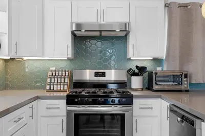a kitchen with white cabinets and a stove top oven at Modern Urban Escape Rooftop & Walkable Fun in San Diego