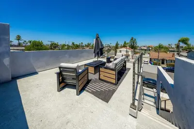 a patio with two chairs and an umbrella on a roof at Modern Urban Escape Rooftop & Walkable Fun in San Diego