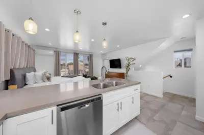 a kitchen with white cabinets and a sink and a couch at Modern Urban Escape Rooftop & Walkable Fun in San Diego