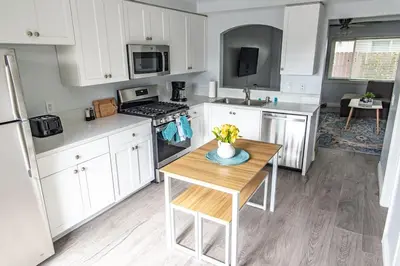 a kitchen with white cabinets and a table with flowers on it at Vibrant Imperial Beach Oasis in Imperial Beach