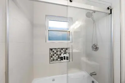 a white bathroom with a shower and a tub at Relaxing Beach Bungalow in San Diego