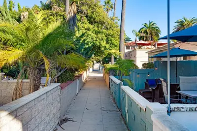 a sidewalk next to a wall with palm trees at Relaxing Beach Bungalow in San Diego